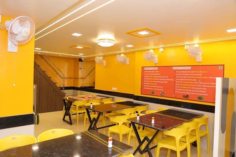 Bright yellow indoor dining hall of a Sampurn Satvik Misal outlet with tables and chairs